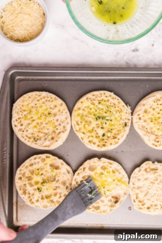 English muffins being brushed with herb butter, preparing them for the Eggs Benedict.