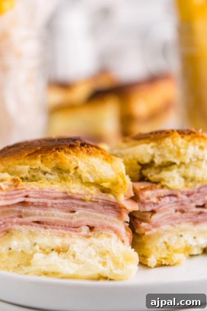Up close picture of three individual ham and cheese sliders, showcasing the melted cheese and toasted bun.
