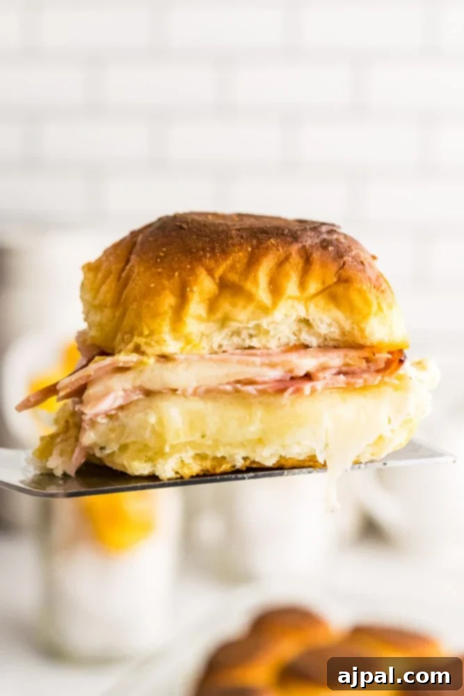 picture of ham and cheese slider in the air on a spatula. 
