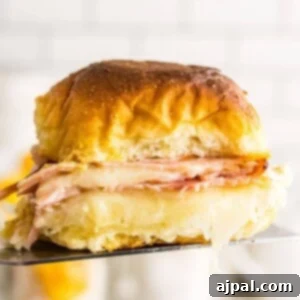 A baked ham and cheese sandwich being held up by a fork.