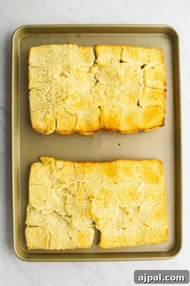 picture of rolls laid out on a sheet pan with butter on them. 