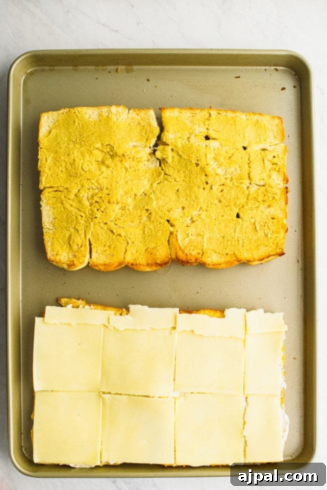 Picture of rolls laid out on a sheet pan, one with cheese on it, other with butter on it.