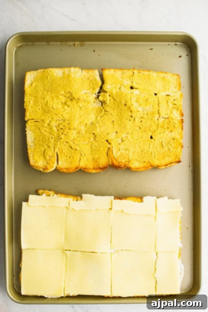 picture of rolls laid out on a sheet pan, one with cheese on it, other with butter on it. 