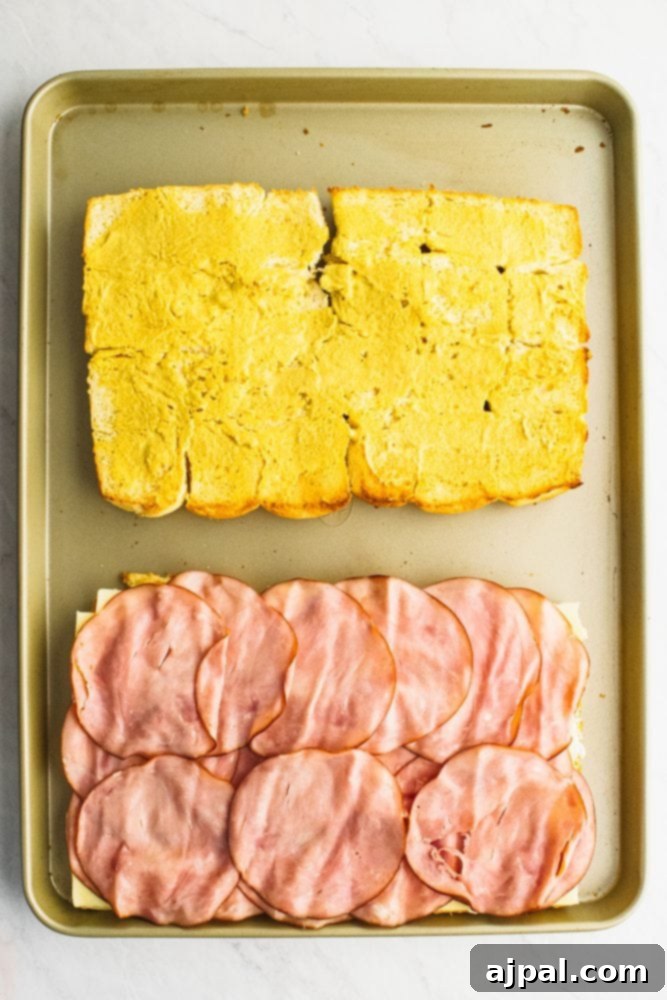 Picture of rolls laid out on a sheet pan, one with ham on it, other with butter on it.