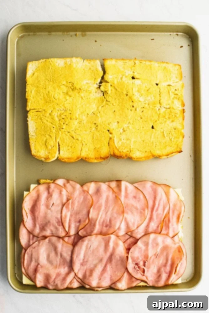 picture of rolls laid out on a sheet pan, one with ham on it, other with butter on it. 