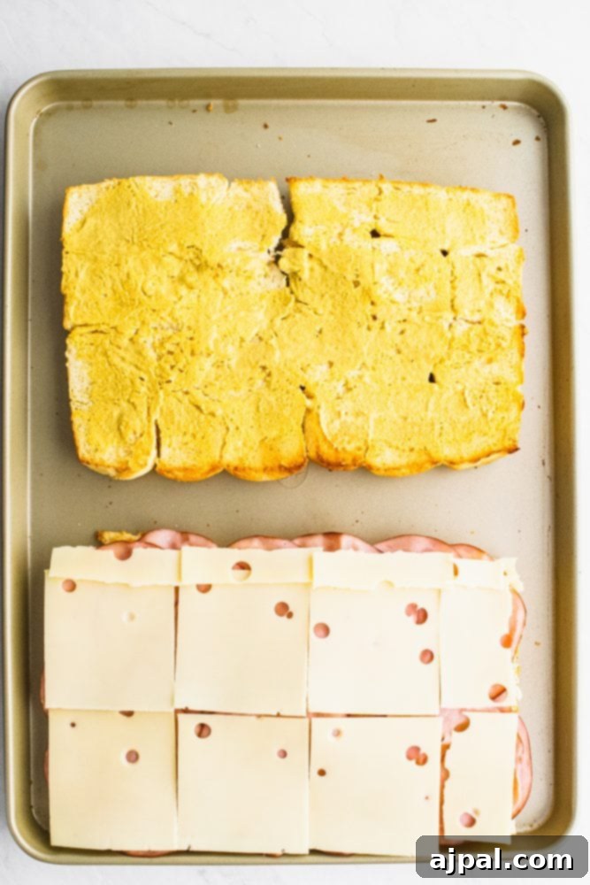 Picture of rolls laid out on a sheet pan, one with cheese on it, other with butter on it.