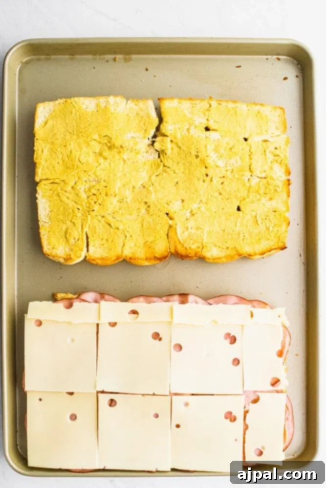 picture of rolls laid out on a sheet pan, one with cheese on it, other with butter on it. 