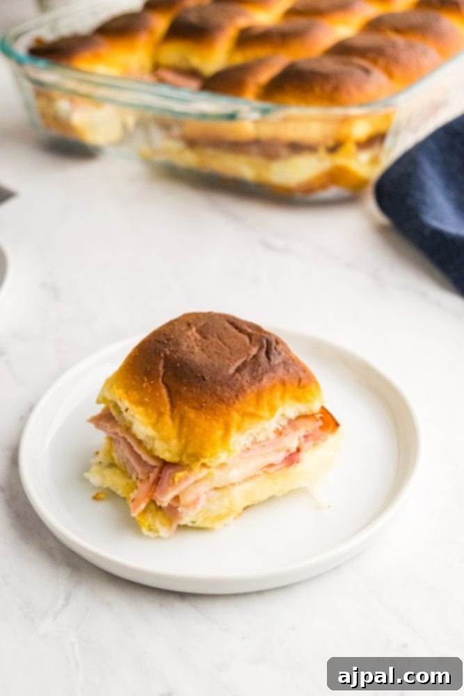 Picture of ham and cheese slider on a white plate, showcasing its golden crust.