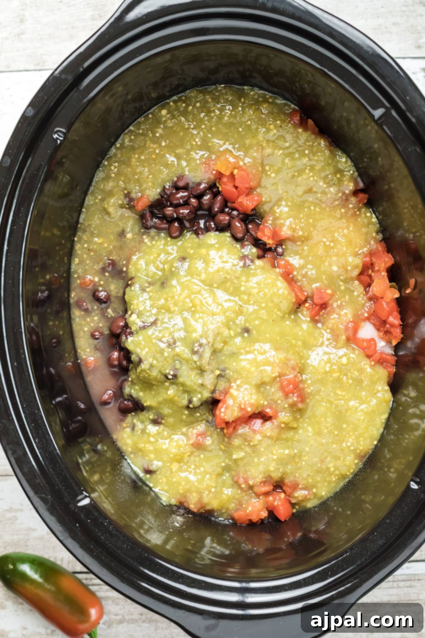 Easy Slow Cooker Chicken Enchilada Soup 11 A crock pot filled with a flavorful slow cooker enchilada soup recipe, featuring guacamole and black beans.