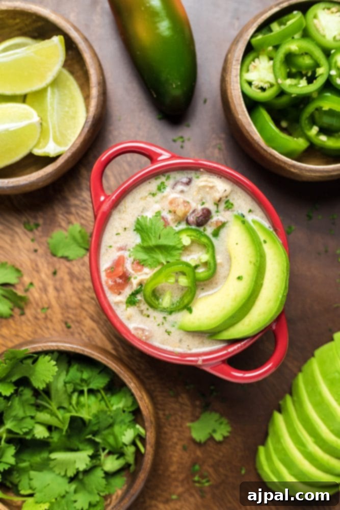 A vibrant bowl of Slow Cooker Chicken Enchilada Soup, garnished with fresh avocado slices and a lime wedge, ready to be enjoyed.