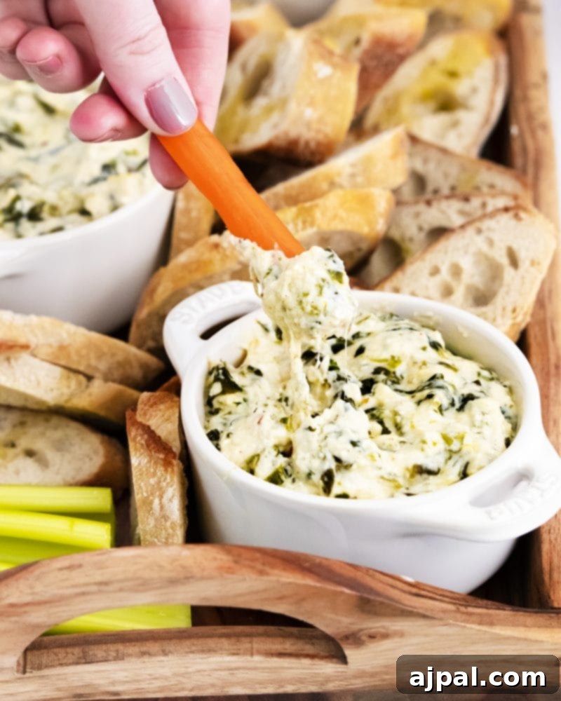 Creamy Instant Pot Spinach Dip 12 A creamy, cheesy spinach dip in a bowl, with a fresh carrot stick dipped into it, highlighting its rich texture and appealing presentation.