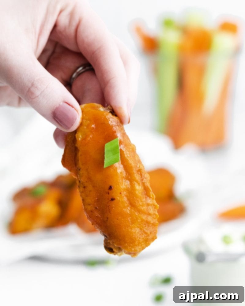 Sticky Sweet Buffalo Wings 2 Crispy honey buffalo chicken wings garnished with fresh green onion, ready to be dipped into a creamy sauce.