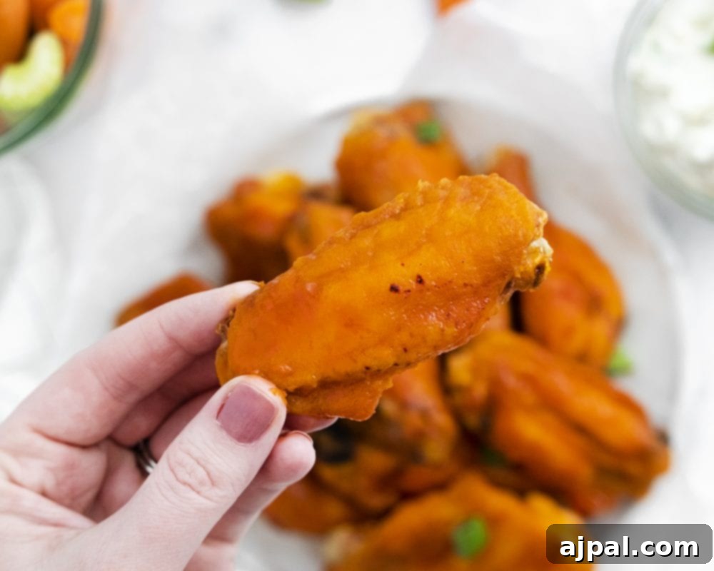 Sticky Sweet Buffalo Wings 6 A hand presenting a plate filled with golden honey buffalo wings, showcasing their delicious glaze.