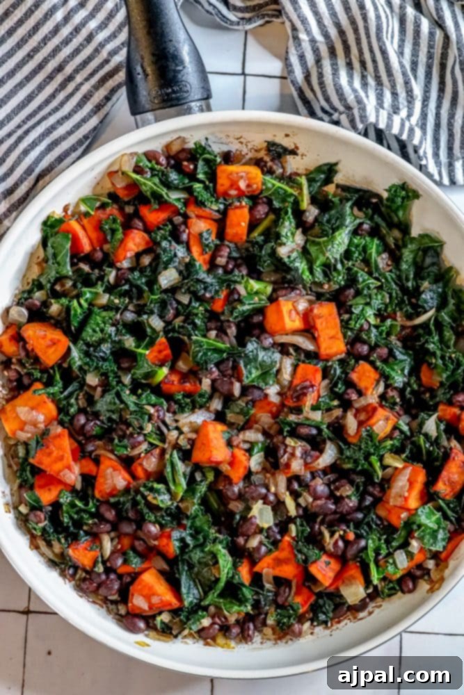 A beautifully composed vegan skillet featuring sweet potato, kale, and black beans, ready to be enjoyed.