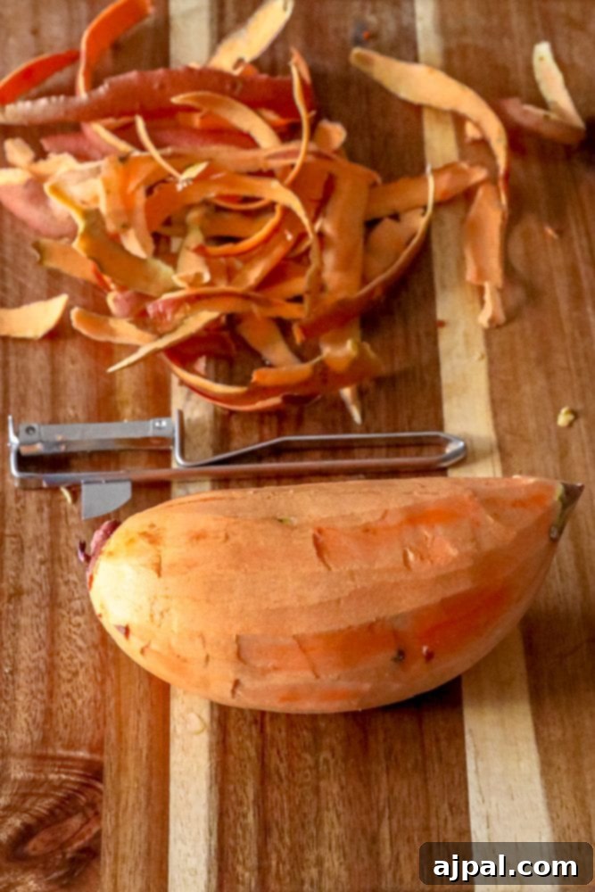 Peeled sweet potato ready for chopping on a wooden cutting board, part of the Sweet Potato Kale and Black Bean Skillet preparation.