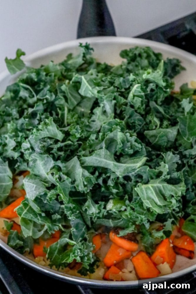 A generous pile of fresh kale added to the skillet with cooked sweet potatoes and onions, just before wilting.