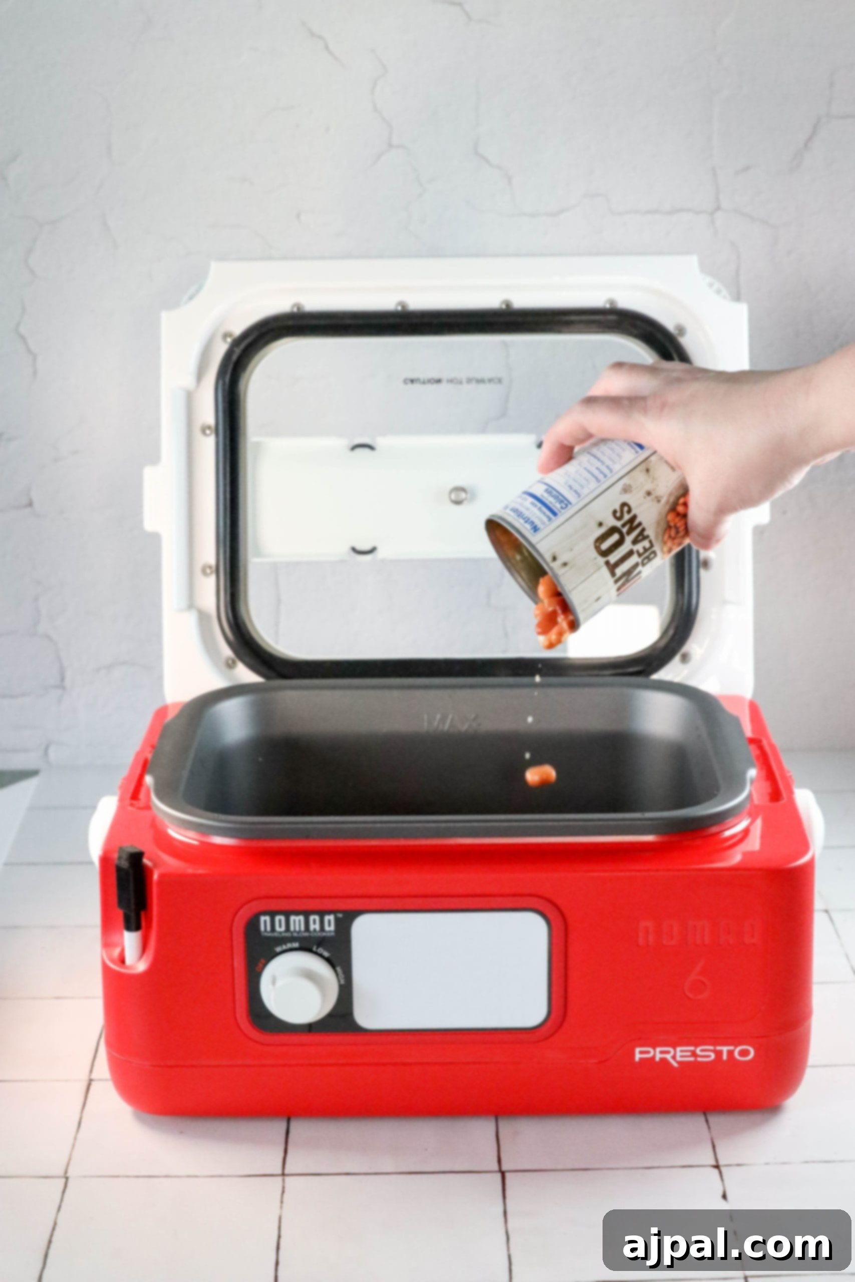 A person is using a red microwave oven to cook an easy bean bake.