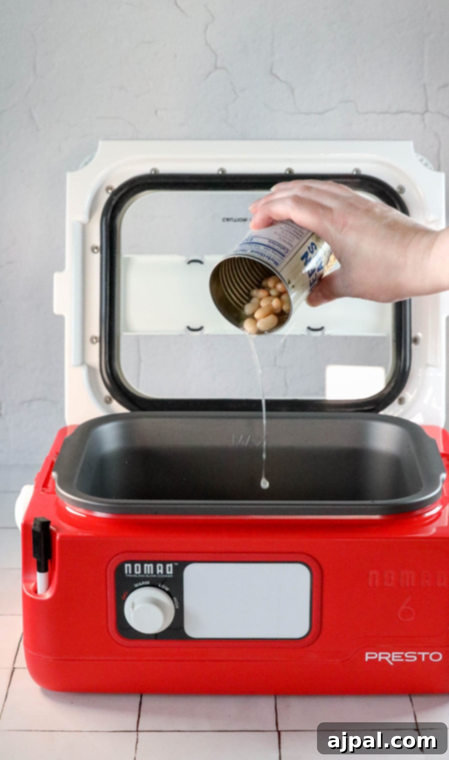 A person is pouring peanuts into a food processor while making the best ever bean bake recipe.