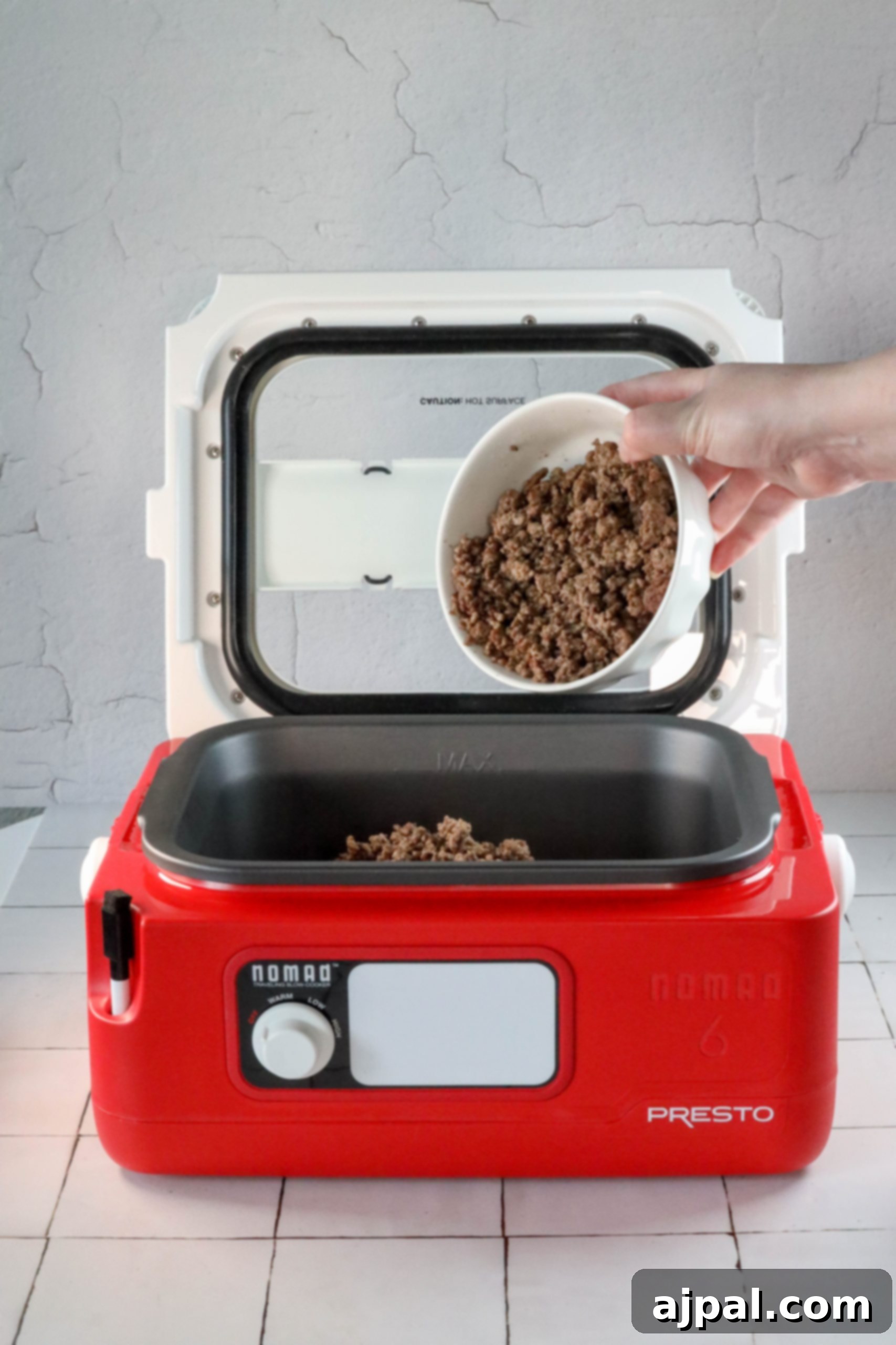 A person is holding a bowl of easy bean bake in a red microwave.