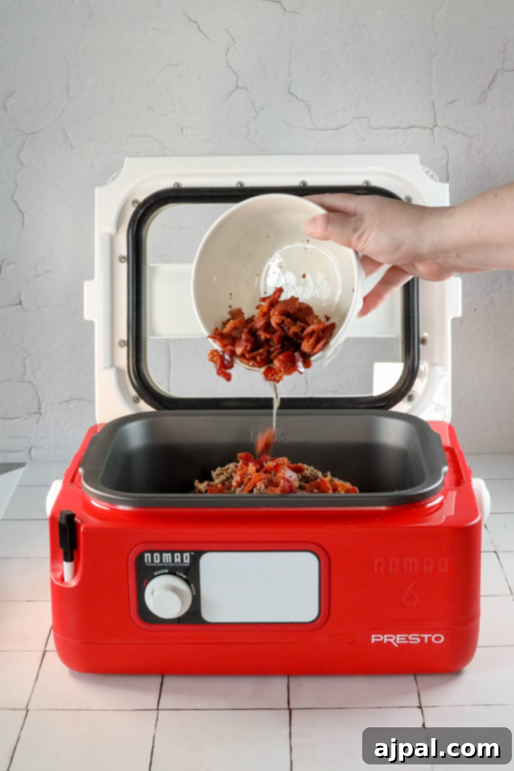 A person is holding a bowl of the best bean bake in a red microwave oven.