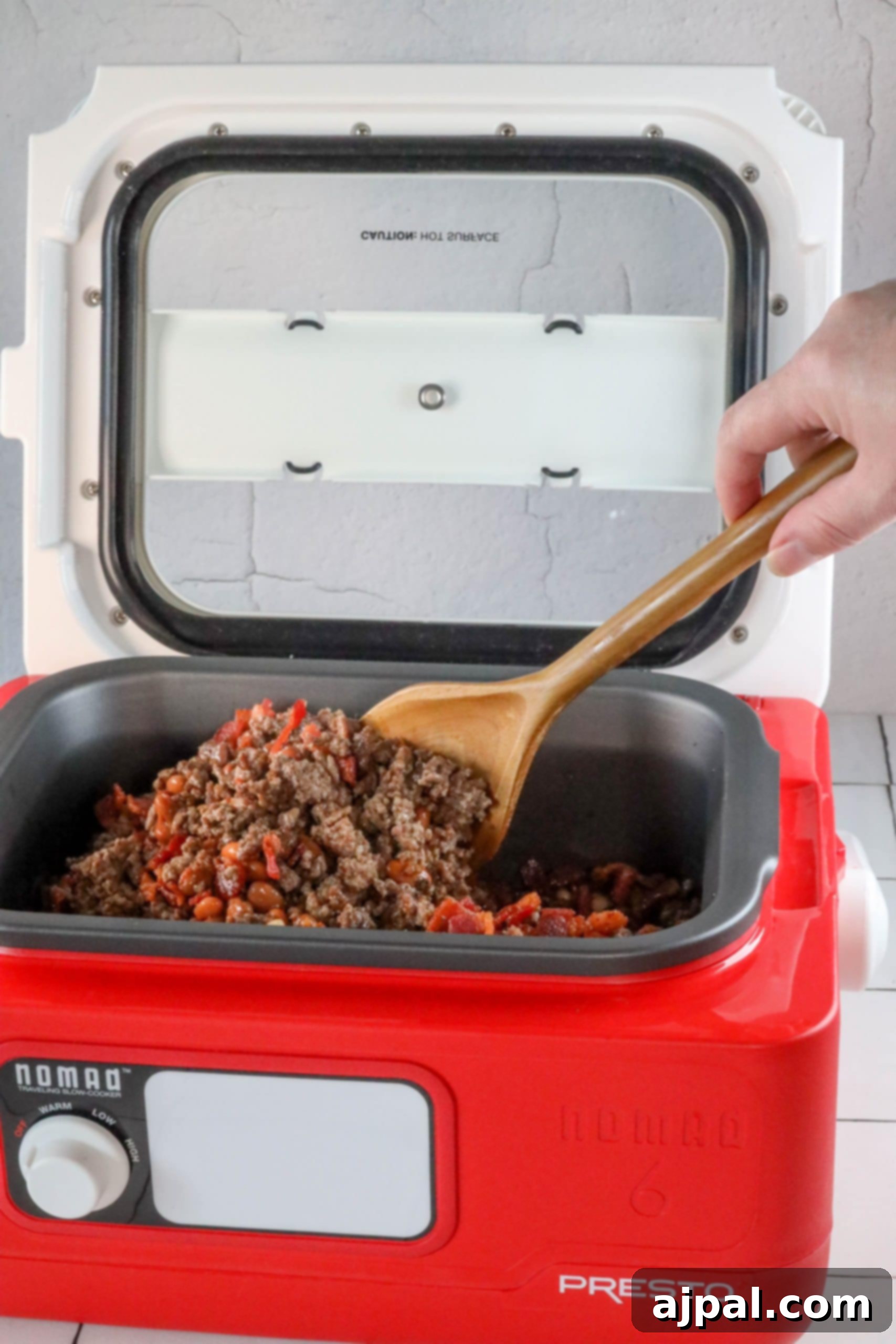 A person is preparing the best ever bean bake recipe using a presto slow cooker.