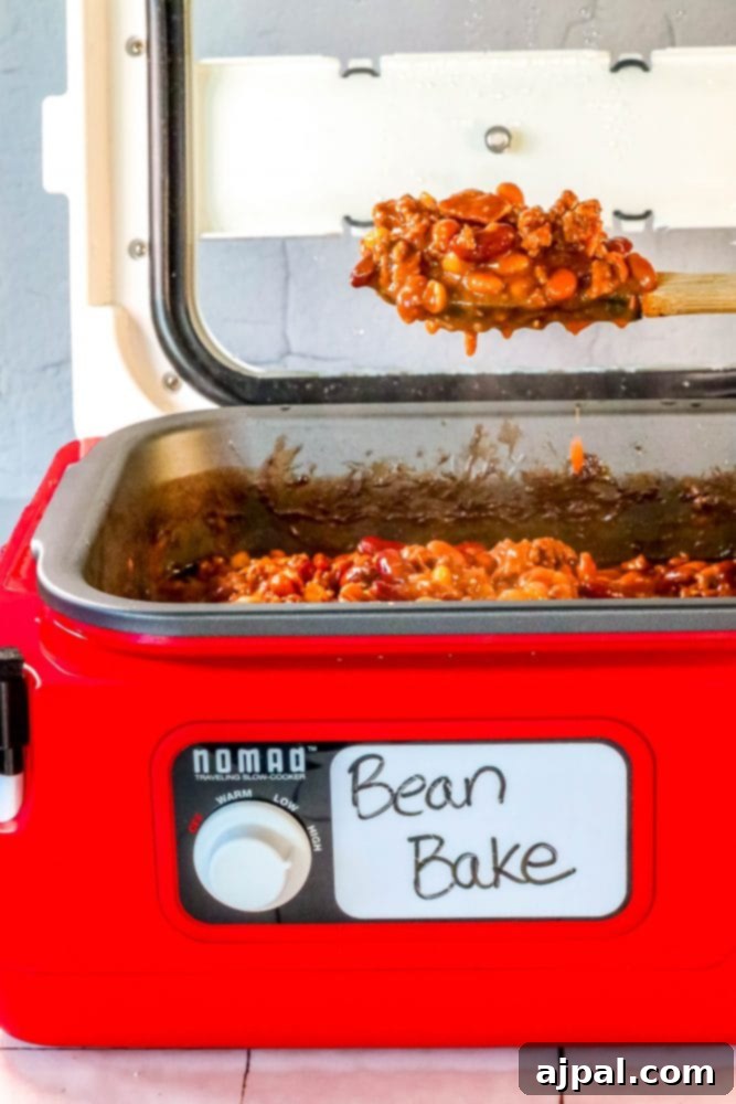 A serving spoon lifting a generous portion of bacon and beef loaded BBQ baked beans, showcasing the rich texture and delicious sauce.