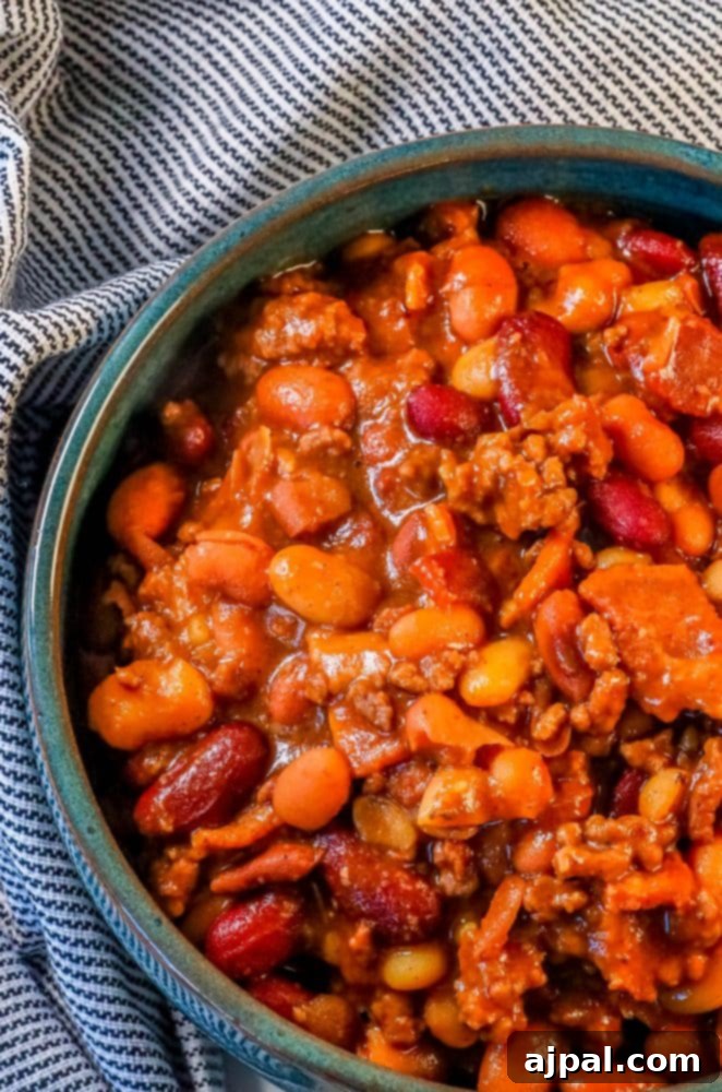 A vibrant blue bowl filled with the best ever BBQ baked beans, highlighting the rich sauce and meaty ingredients.