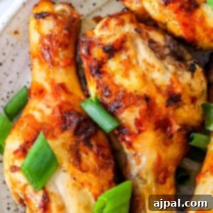 Chicken wings with piri piri seasoning served on a white plate garnished with green onions.