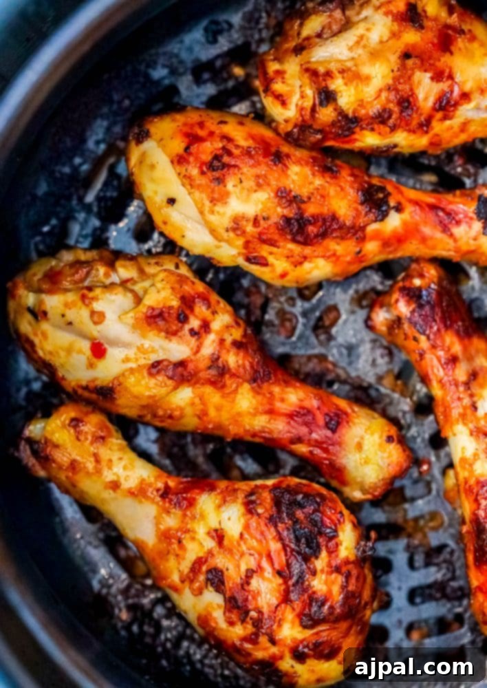 Crispy air-fried piri piri chicken drumsticks perfectly arranged in an air fryer basket, showing their golden-brown, inviting texture.