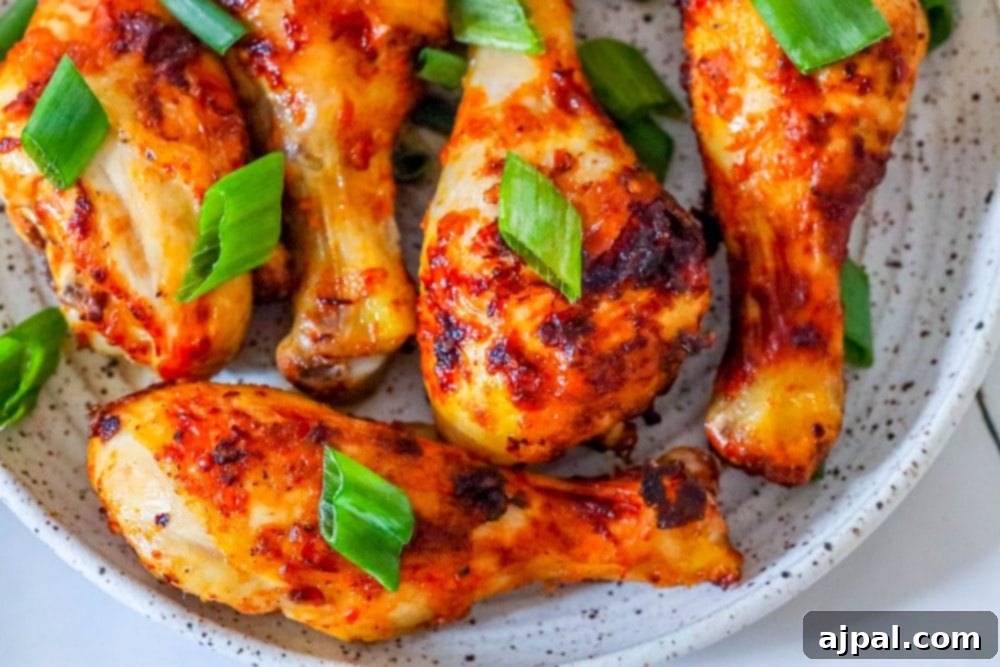 A beautifully arranged platter of air-fried piri piri chicken legs with vibrant basil leaves, showcasing their crispy skin and rich color.