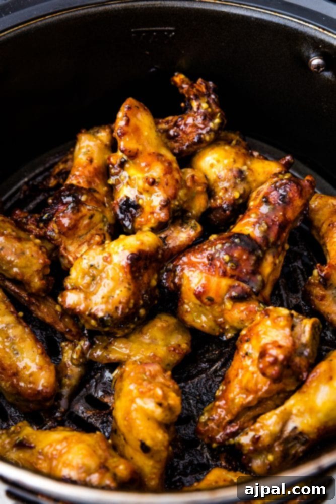 Air Fried Honey Mustard Glazed Wings 2 Sticky honey mustard chicken wings in an air fryer basket, glistening with sauce.
