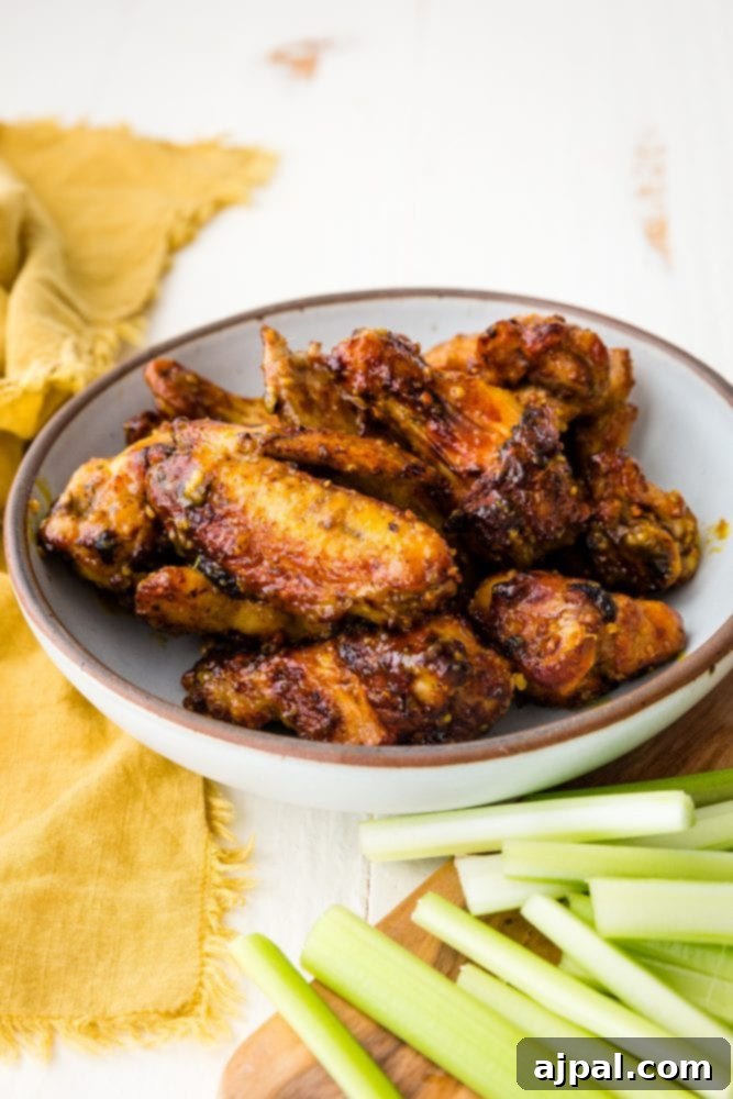 Air Fried Honey Mustard Glazed Wings 3 Plate of sticky honey mustard chicken wings garnished with celery sticks.
