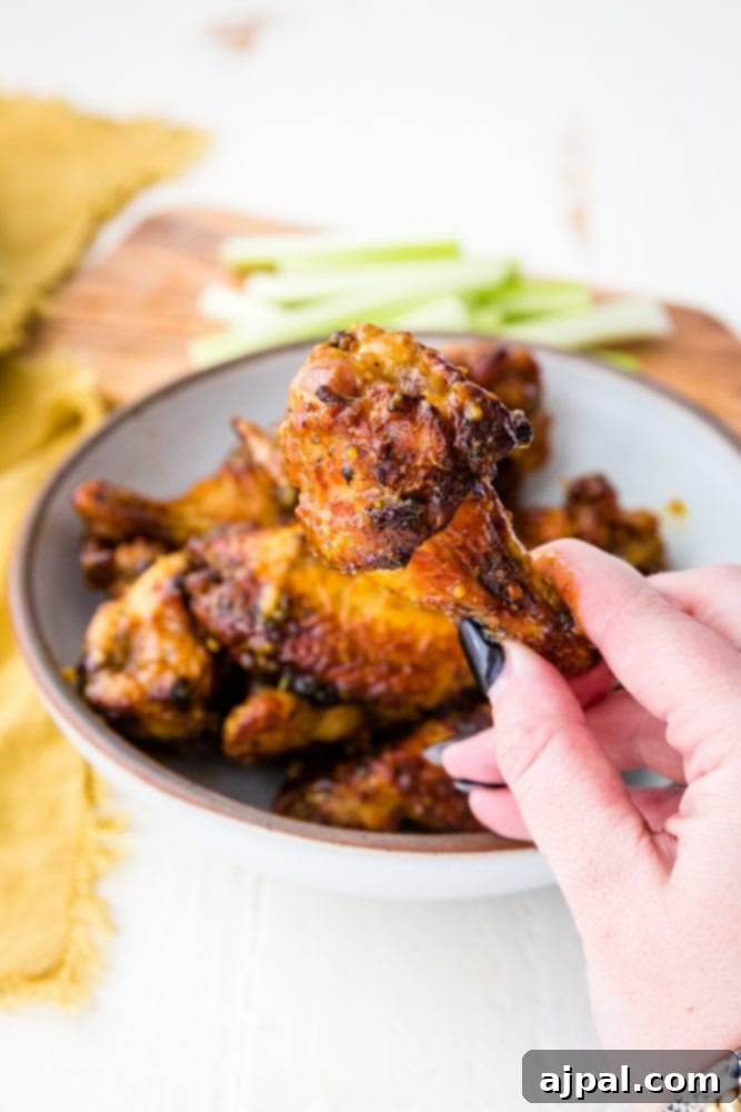 Air Fried Honey Mustard Glazed Wings 4 A hand holding a bowl of sticky honey mustard chicken wings.