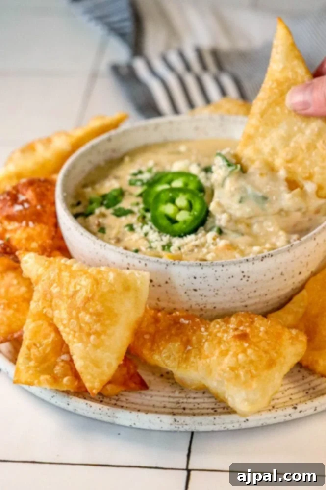 Hamburger White Queso Dip 4 A person holding a bowl of creamy white cheese hamburger queso dip, ready to be served with tortilla chips.