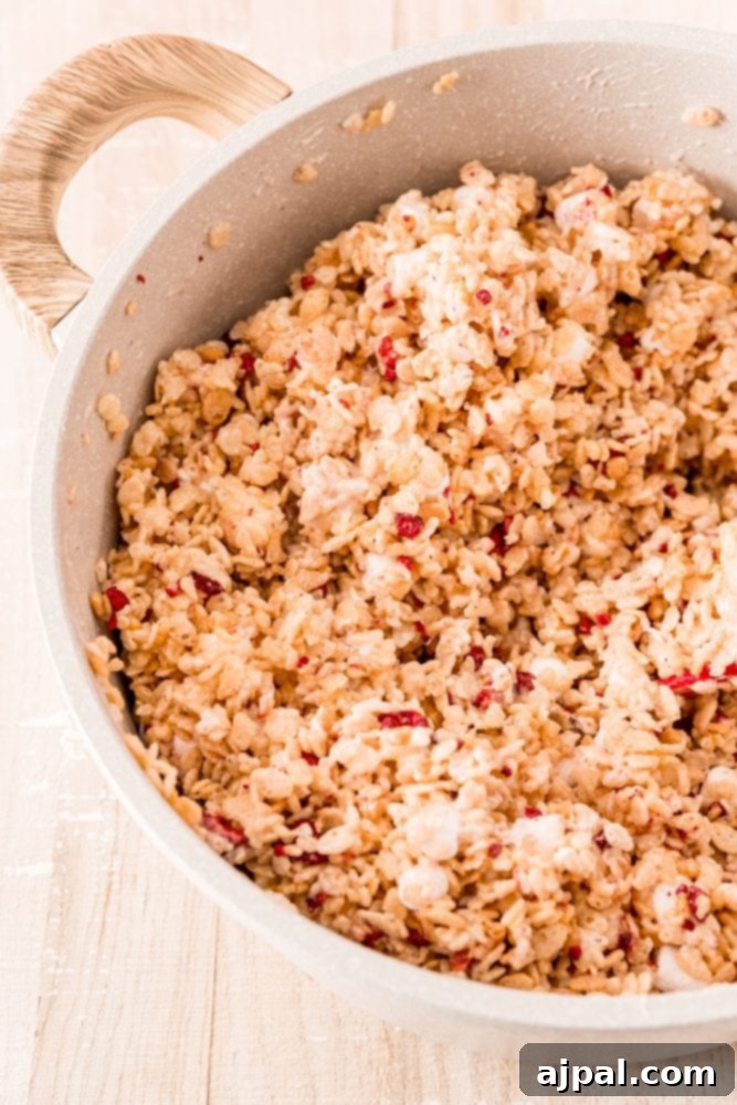 White Chocolate Raspberry Krispie Delights 11 Rice Krispie cereal in a bowl, coated with melted marshmallow, showing the sticky mixture.