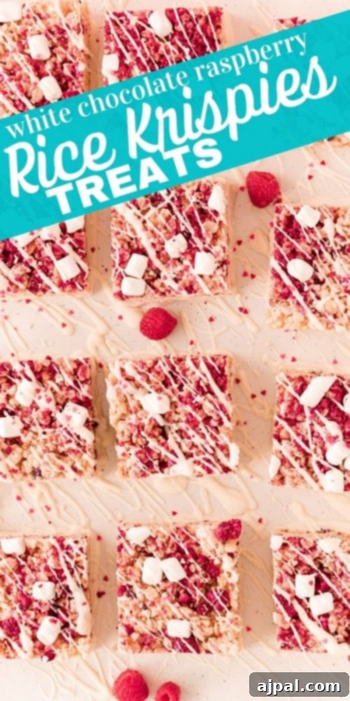 White Chocolate Raspberry Krispie Delights 14 A vibrant pink Rice Krispie treat, featuring visible marshmallows, freeze-dried raspberries, and a delicate white chocolate drizzle.