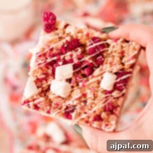 A hand holding up a piece of raspberry granola.