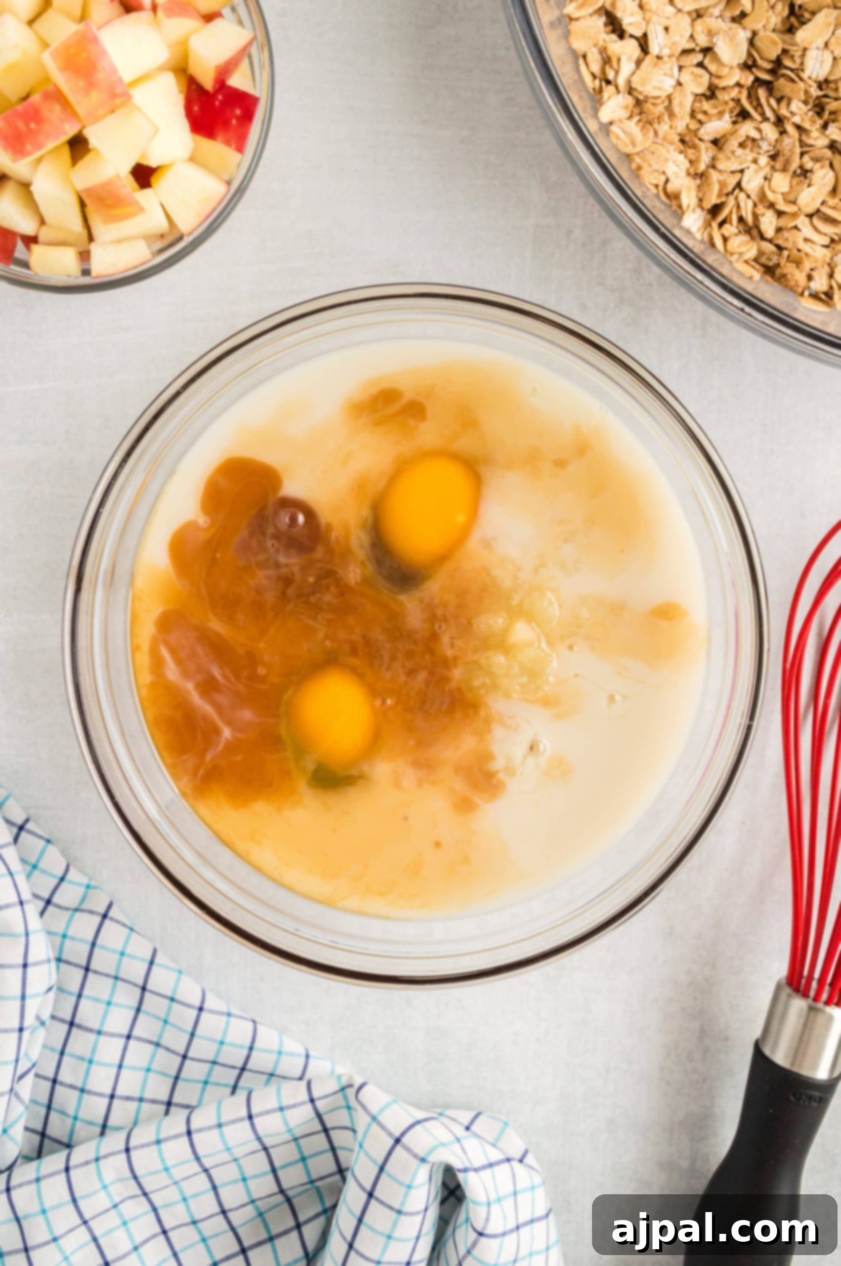 The essentials for easy baked oatmeal: fresh apples and a gleaming whisk, poised for mixing.