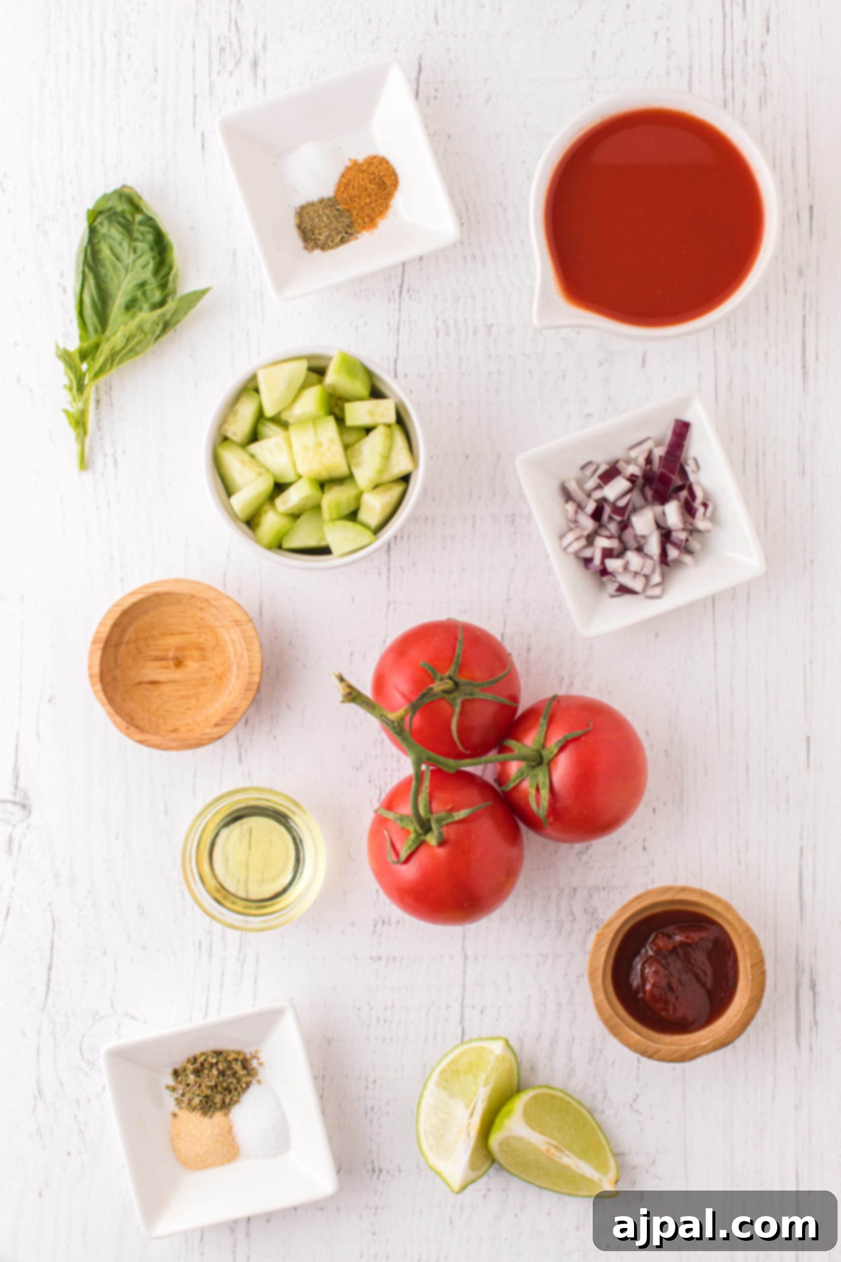 Fresh ingredients laid out for a Gazpacho recipe, including tomatoes, cucumber, onion, and herbs.