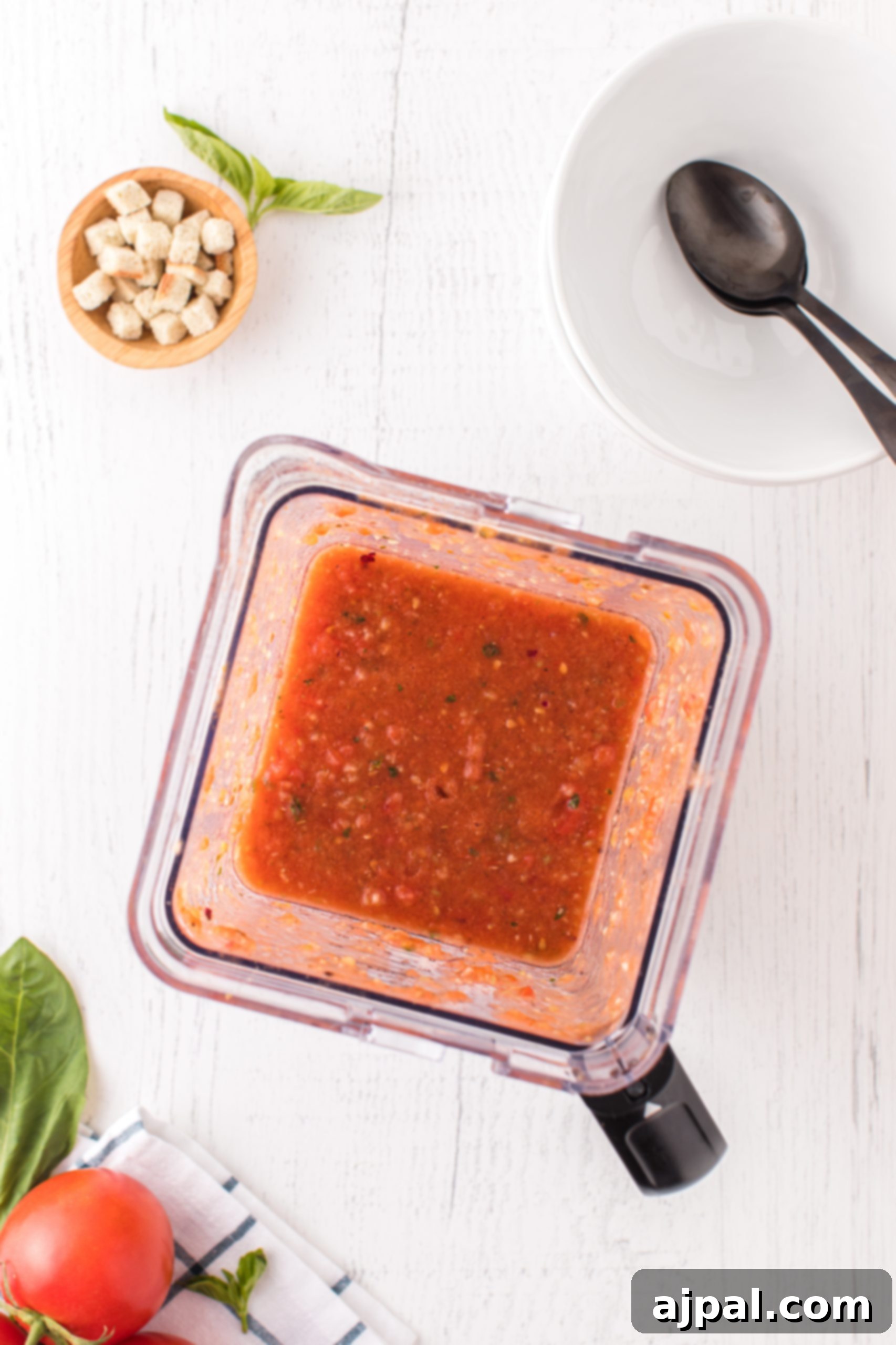 Tomato sauce being blended in a food processor, highlighting the smooth preparation process for gazpacho.