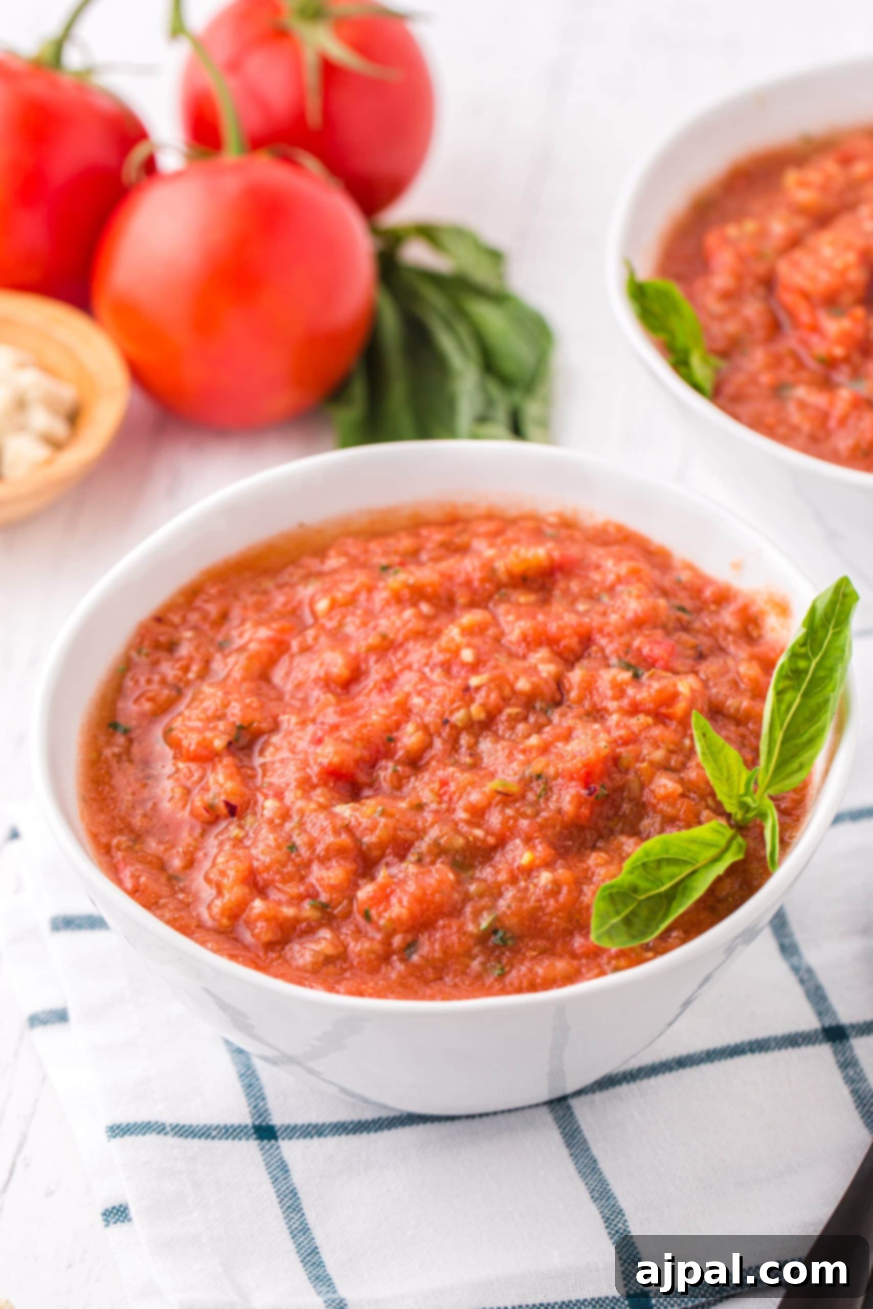 Two bowls of freshly prepared gazpacho soup, garnished and ready to be enjoyed on a wooden table.