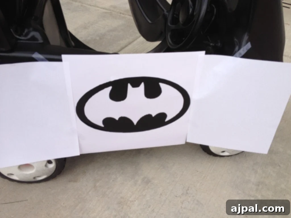 picture of black painted cozy coupe car with a paper stencil over it 