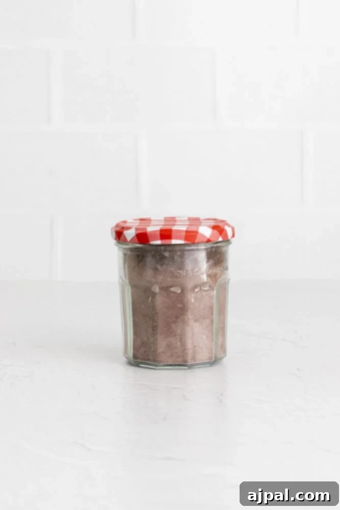 Decadent Peanut Butter Hot Cocoa Bombs 15 Brown hot chocolate mix in a glass jar with a checkered top, ready to be used as filling.