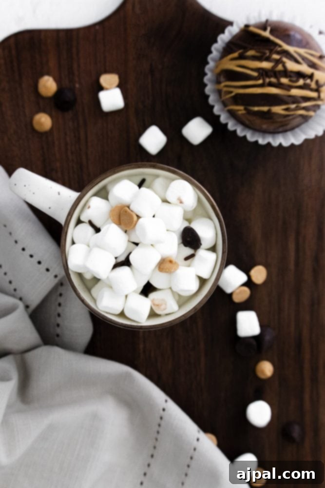 Decadent Peanut Butter Hot Cocoa Bombs 3 Mug full of marshmallows and chocolate chips on a wooden countertop, ready for a delicious hot chocolate bomb.
