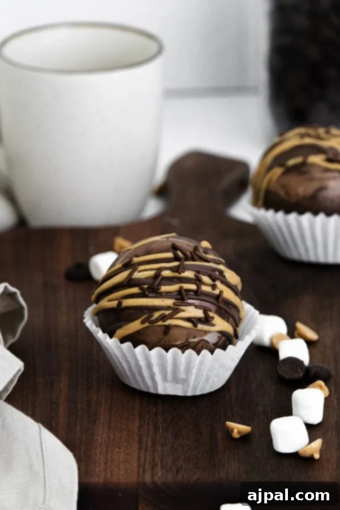Decadent Peanut Butter Hot Cocoa Bombs 4 Peanut butter hot chocolate bombs with peanut butter and chocolate sprinkles, marshmallows in the background, showcasing the rich, detailed topping.