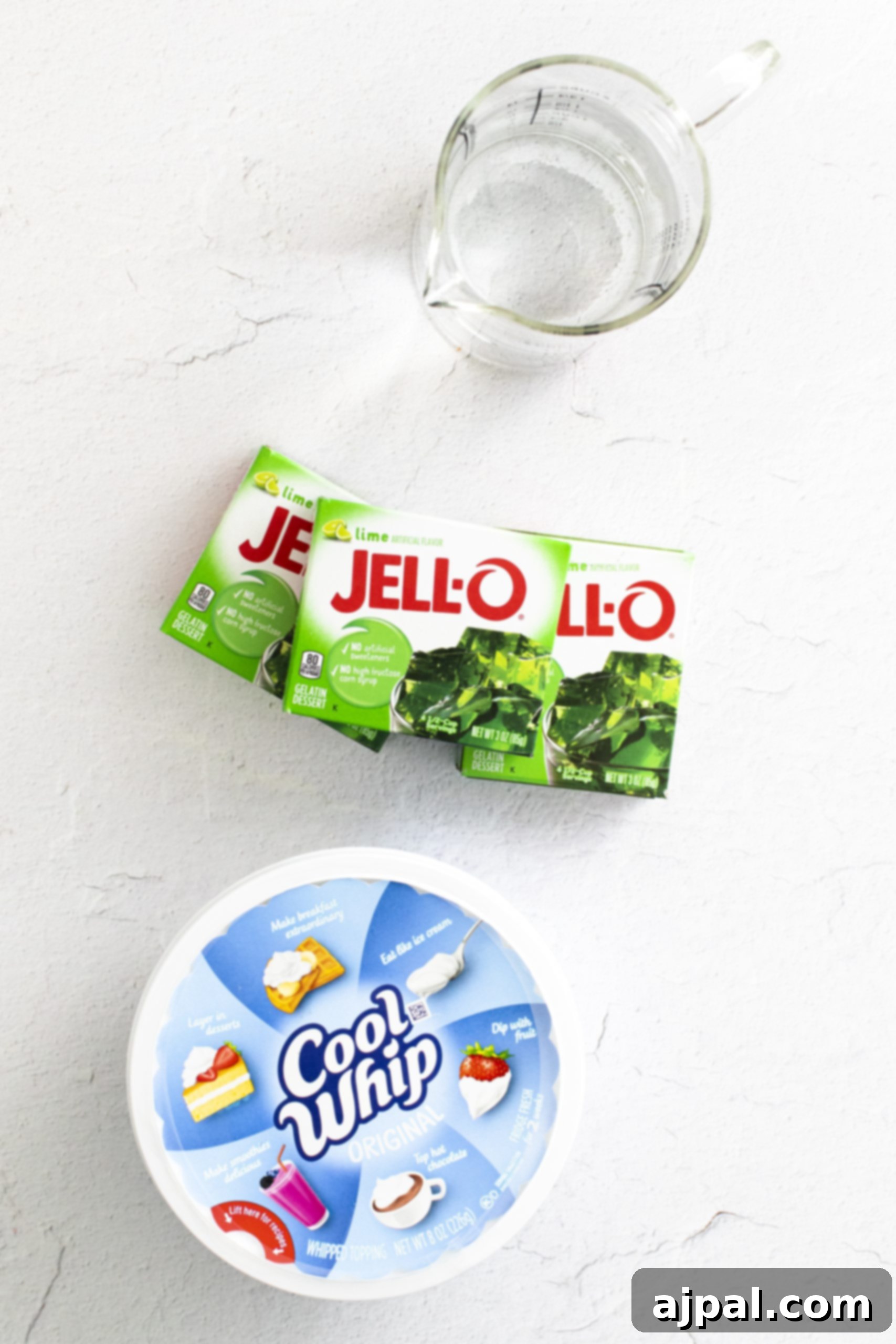 A bowl of layered green jello next to a glass of water.