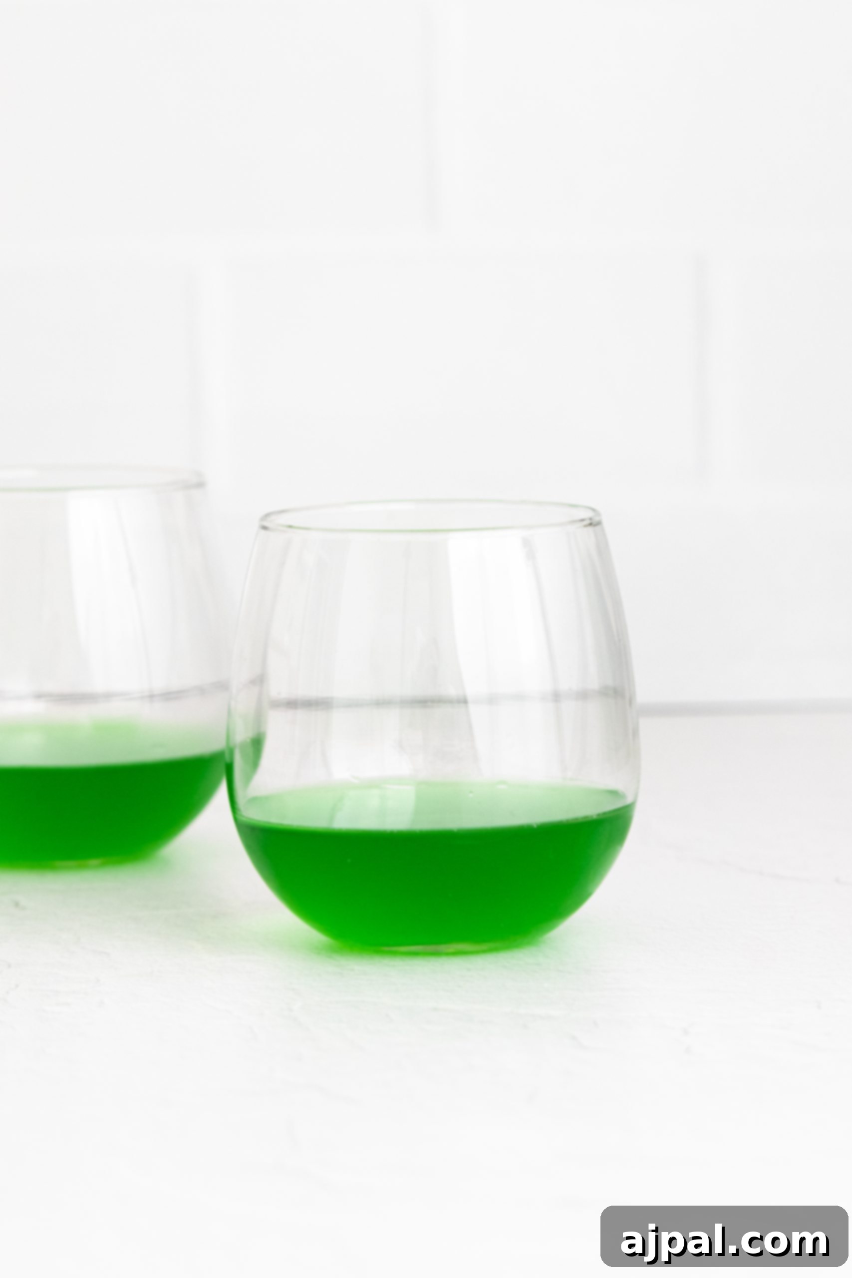 Two glasses with layered green jello and whipped cream cups.