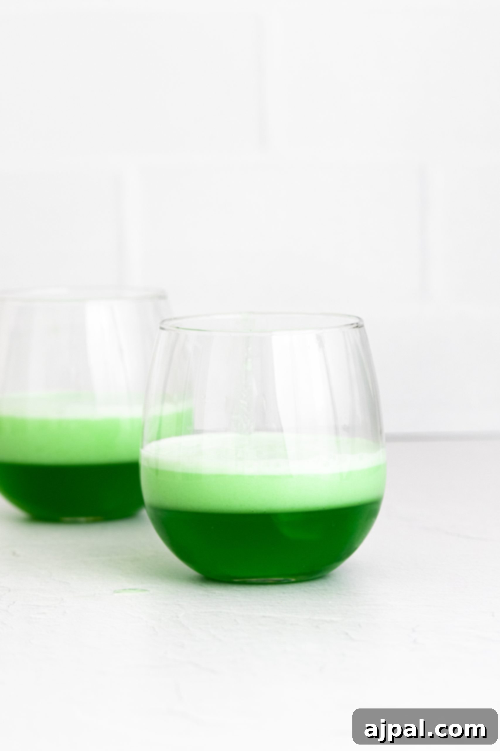 Two glasses with layered green jello and whipped cream cups as an easy jello dessert.