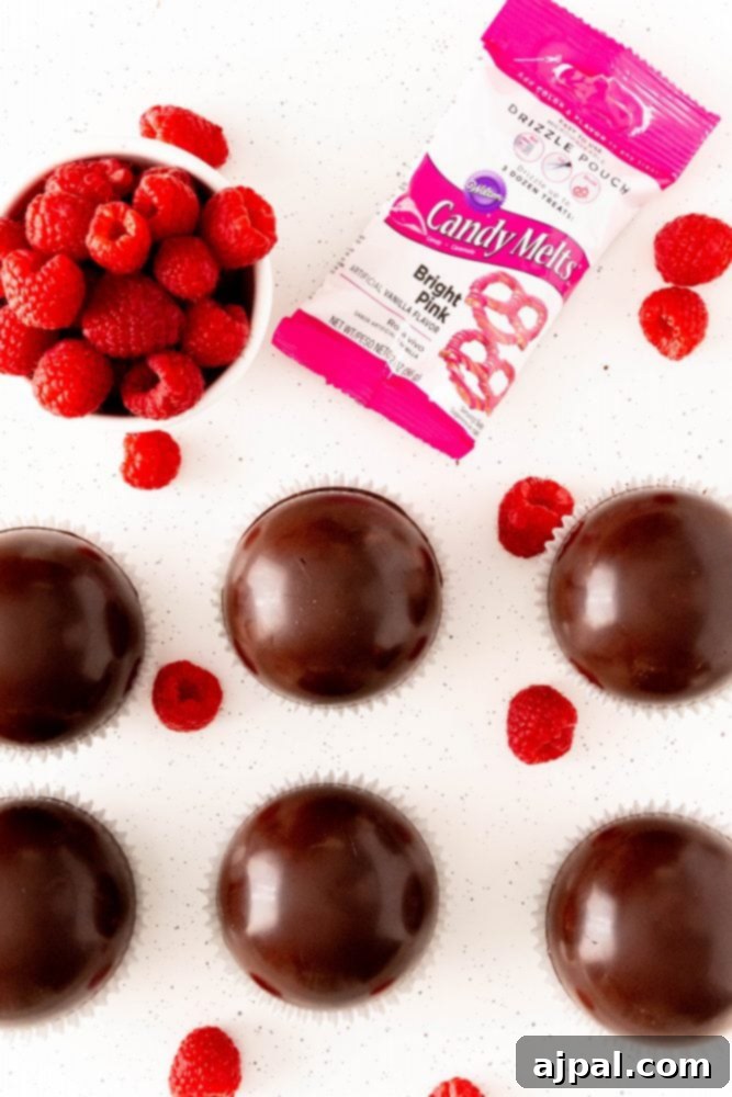 Berry Burst Hot Cocoa Spheres 19 Raspberry truffles and chocolate components on a white surface, showcasing bomb construction.
