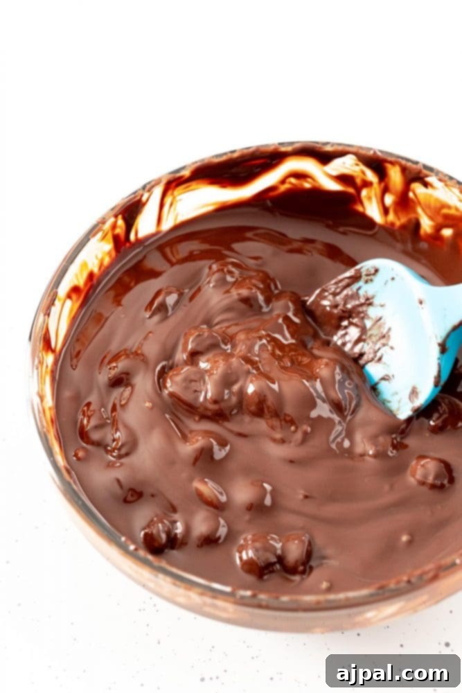 Berry Burst Hot Cocoa Spheres 7 Clumpy chocolate being stirred in a bowl during the tempering process.